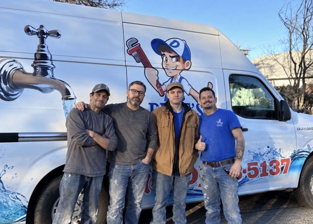 Four plumbing team members standing together in front of a branded service van